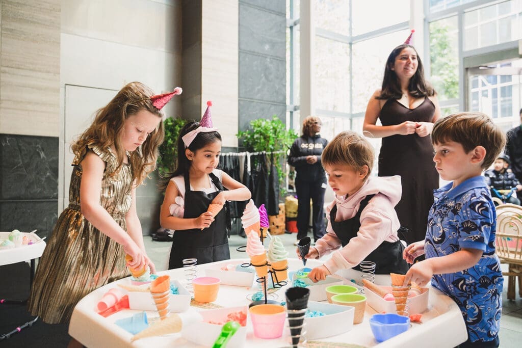 Photo of kids playing around a table with ice cream making set up designed and organized by Oogubi events and photographed by Mini Anna Photography
