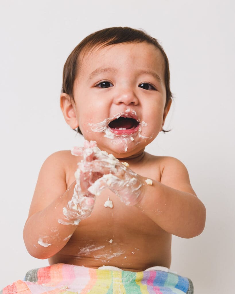 Cake-covered toddler laughing during shoot in Sausalito
