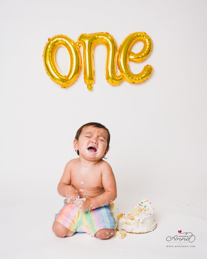 Baby covered in frosting after cake smash
