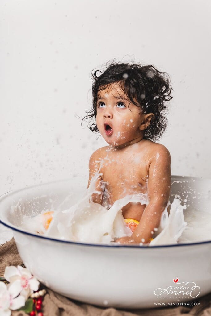 Newborn in milk bath with soft natural light