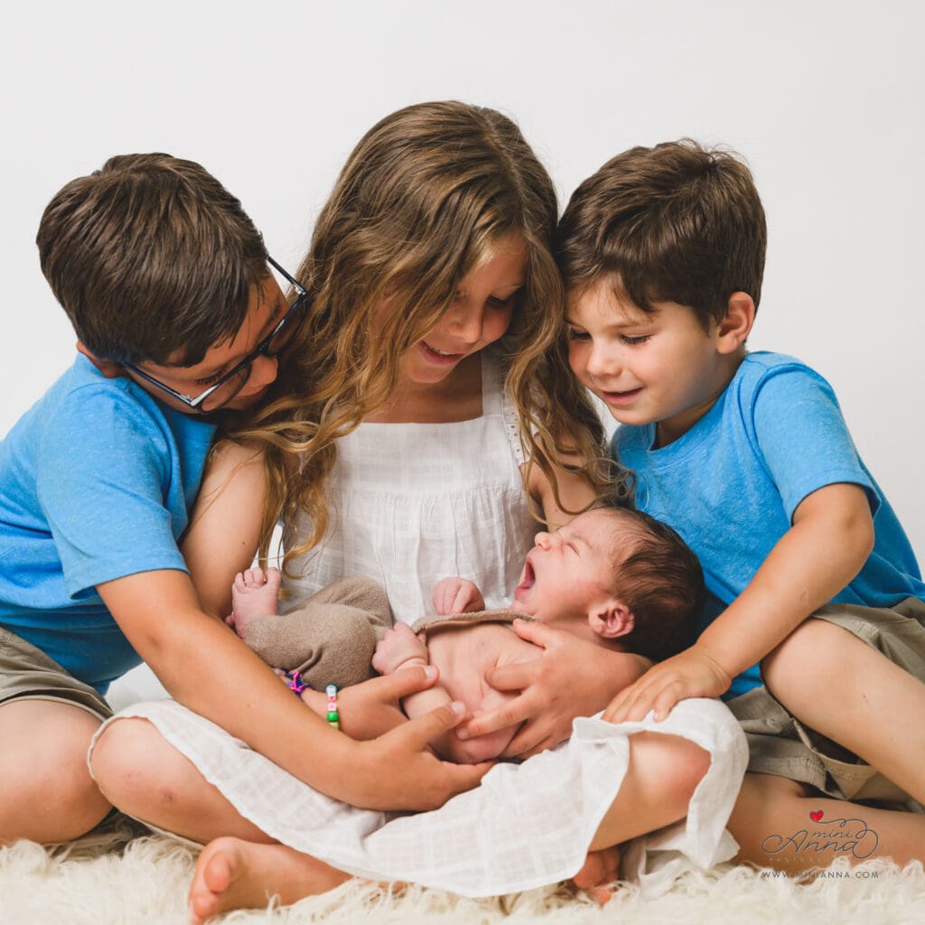 Family cuddling their newborn in studio