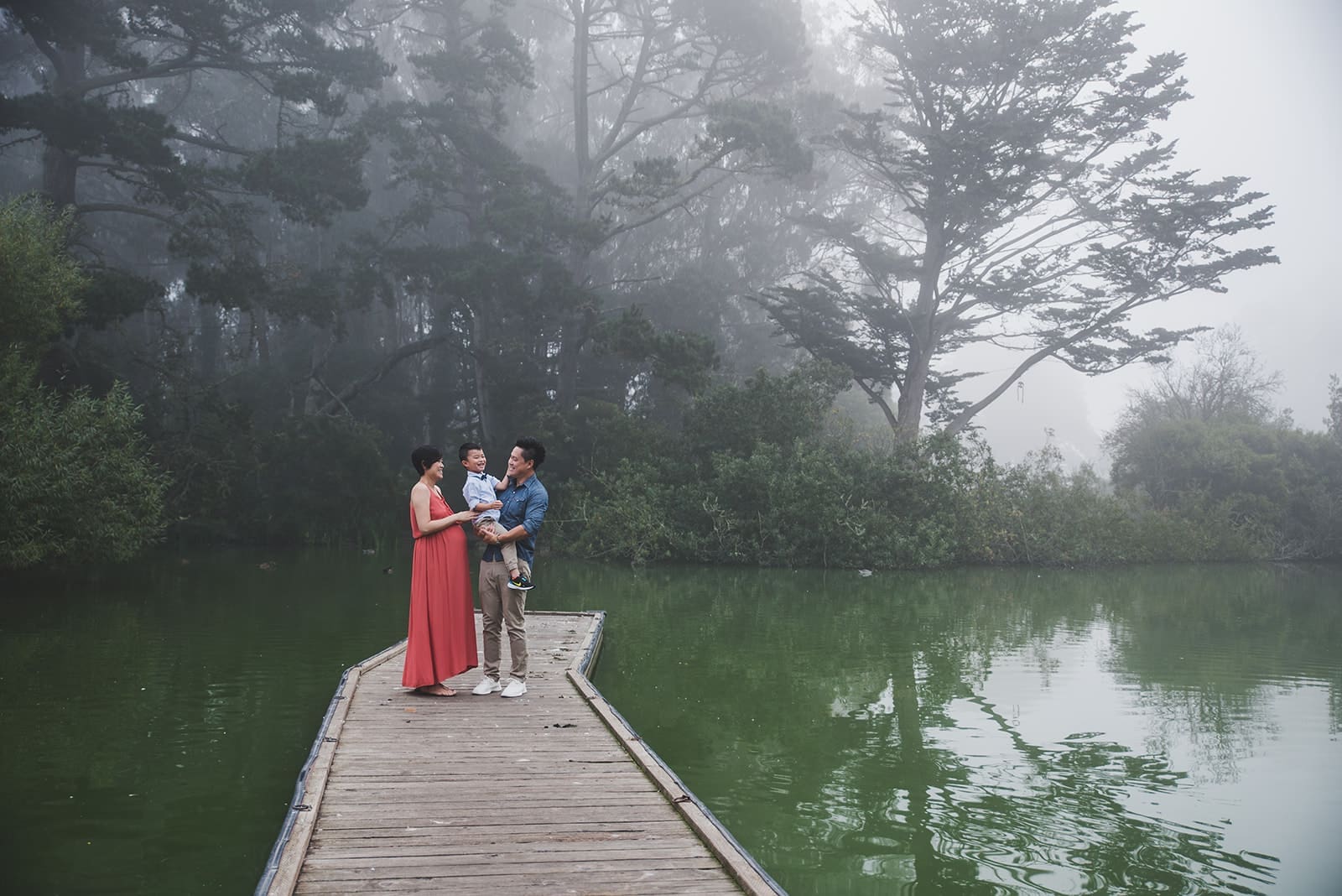 Playful family photo session at Blue Heron Lake in Golden Gate Park with water views, a cute white bridge and tree line paths. 