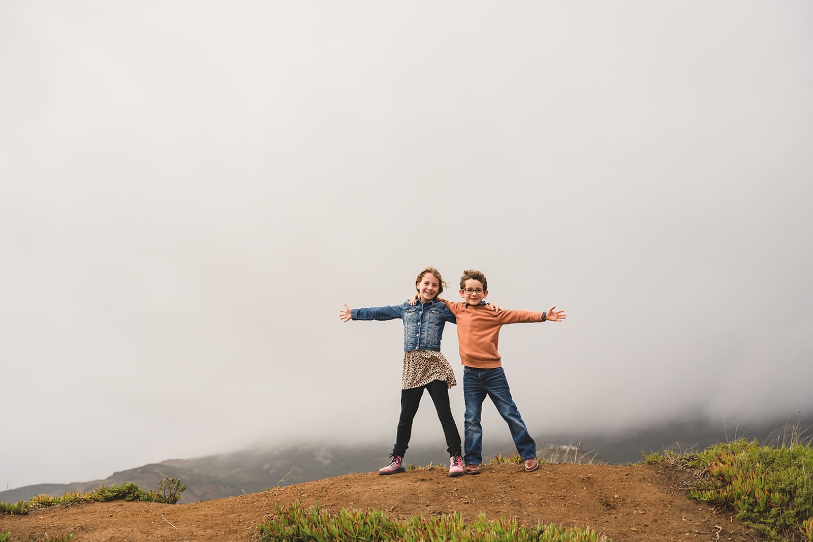Candid family photos at Marin Headlands with coastal cliffs, golden sunset light, and wind-swept movement
