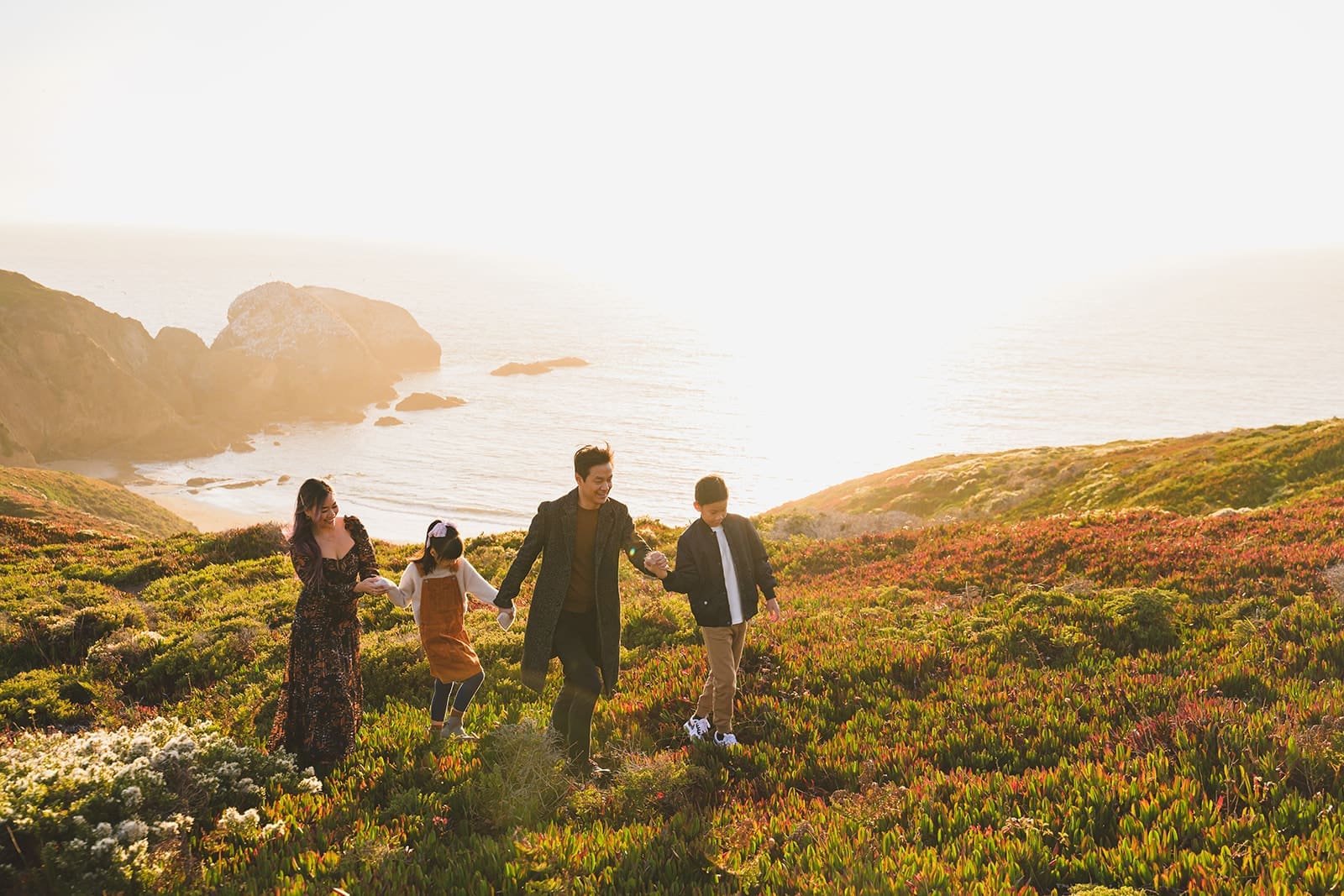 Candid family photos at Marin Headlands with coastal cliffs, golden sunset light, and wind-swept movement