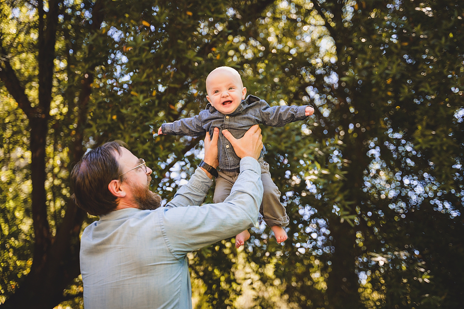 dad lifts up baby in the air by Marin and San Francisco family photographer