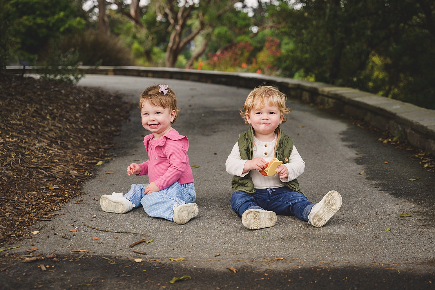 twin toddlers sit on park path showing what to wear for family photos